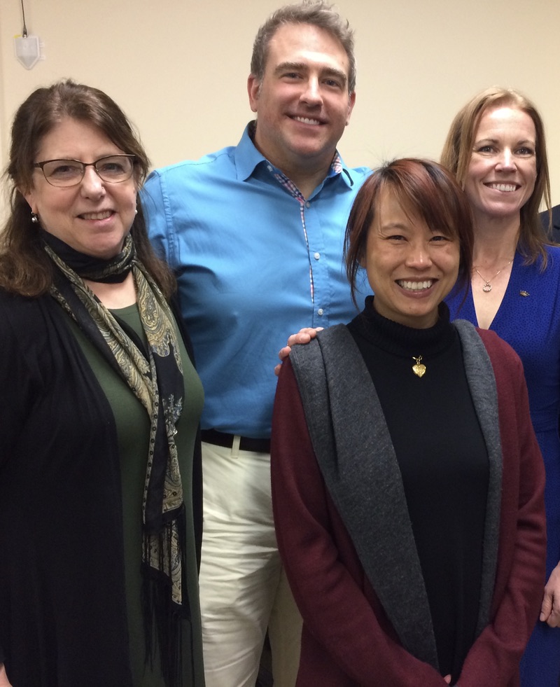 Dr. Yen Verhoeven smiling at her defense, with committee members from University of Rochester, including Dr. Jayne, behind her.