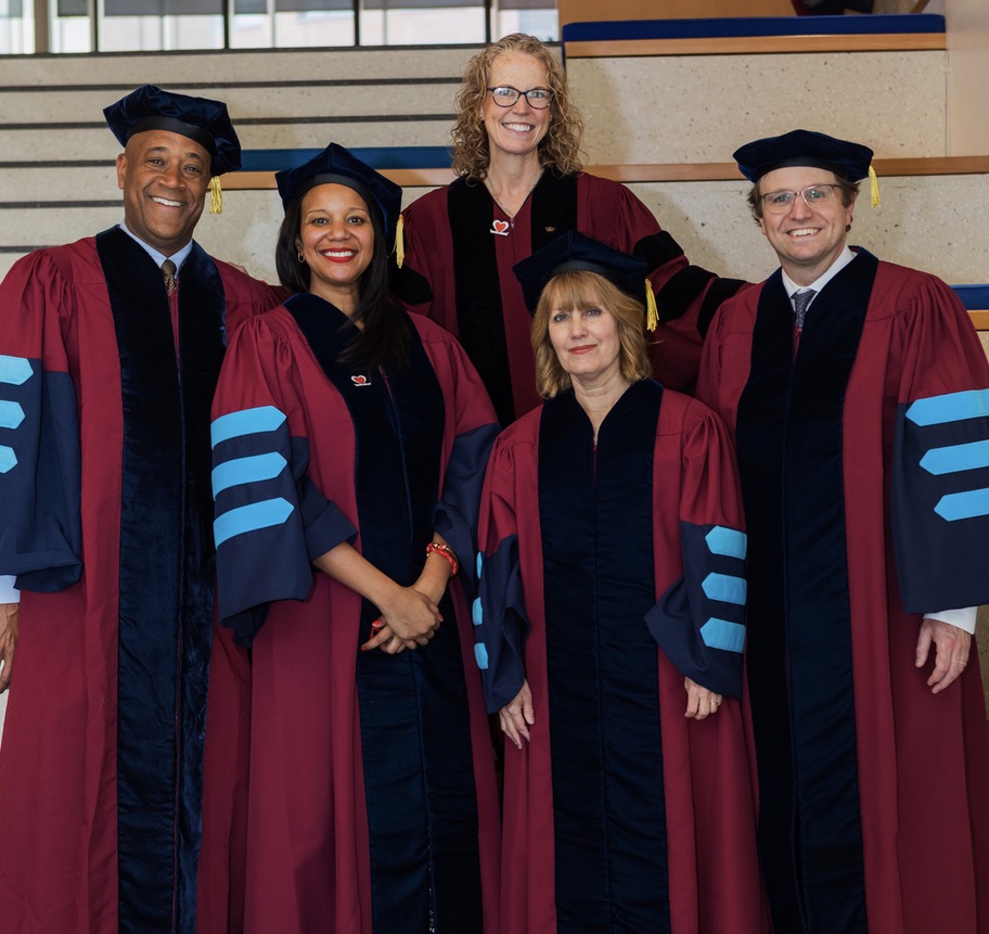 Dr. Jayne standing behind 4 Penn doctoral students - all are wearing academic regalia